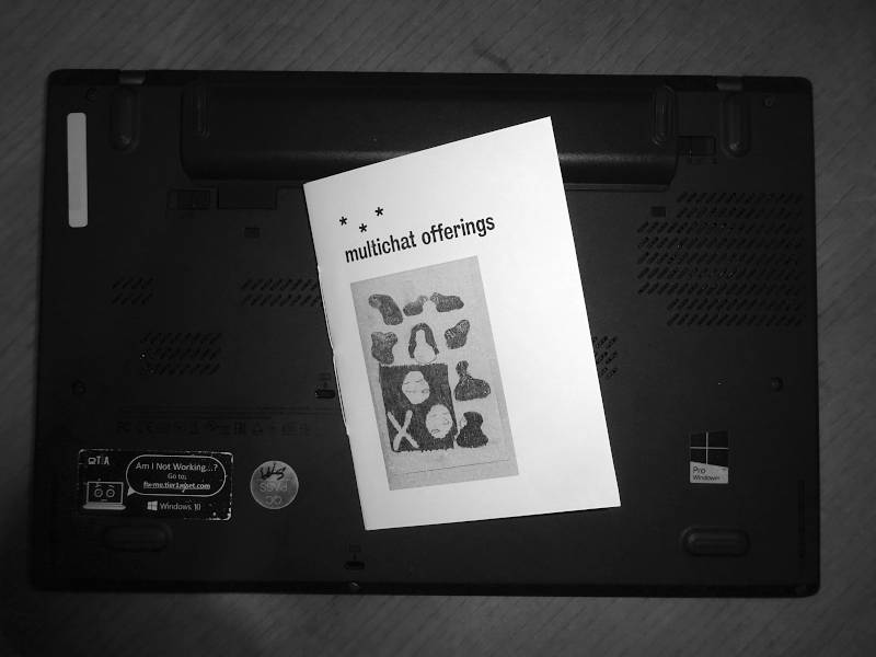 printed copy of a small book laying on the backside of a laptop. Title: multichat offerings.